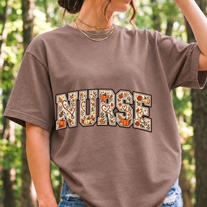 Arched varsity word NURSE filled with autumn leaves, stethoscopes and pumpkins in cream, rust and mustard