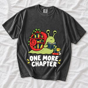 Cartoon snail reading a book with a bookshelf shell and the text One More Chapter