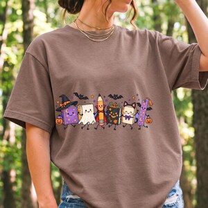 Kawaii books, pencil and bookmark with faces in Halloween costumes, pastel purple and orange