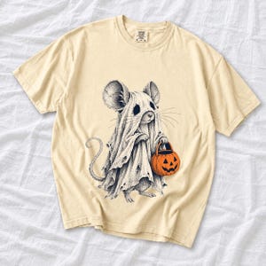 Etched pen illustration of a small mouse in a sheet ghost costume holding a candy bucket, bone white with orange accent