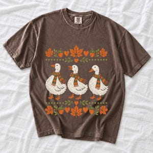 Three white ducks in striped scarves with acorn and maple leaf borders, retro screen print fall t-shirt art