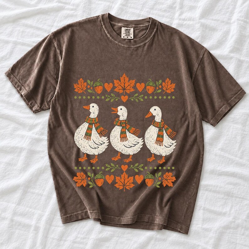 Three white ducks in striped scarves with acorn and maple leaf borders, retro screen print fall t-shirt art