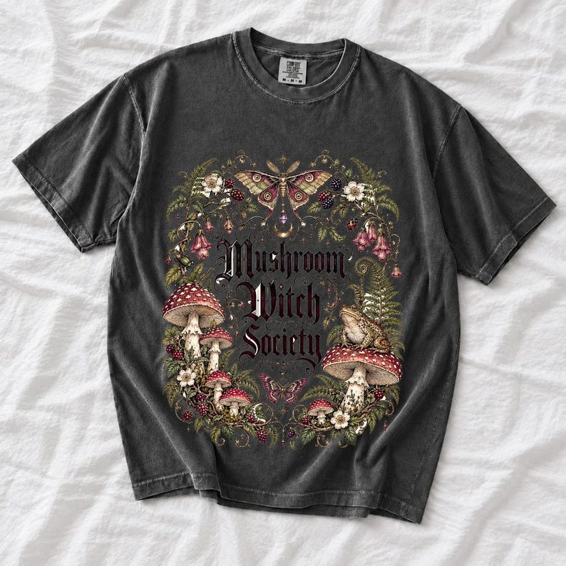 Blackletter text "Mushroom Witch Society" framed by fly agaric mushrooms, ferns and a toad on a mushroom cap