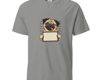 May include: A grey short-sleeve t-shirt featuring a graphic of a tan pug with a black face, winking and sticking its tongue out. The pug is holding a blank rectangular sign with a black border, set against a background of horizontal lines.