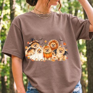 Five fluffy watercolor pomeranians in Halloween costumes with autumn leaves and bats