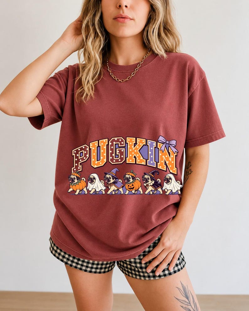 Six pugs in pumpkin, ghost and witch costumes under the arched word PUGKIN, lavender and orange polka-dot varsity style
