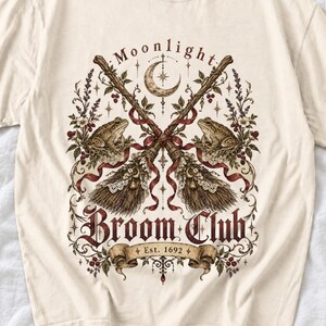 Vintage poster style crossed broomsticks with ribbons, lace and toads, text Moonlight Broom Club Est. 1692