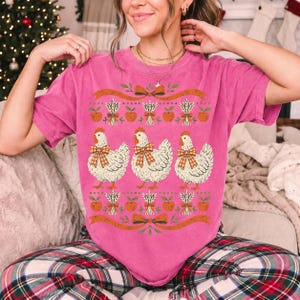 Three fluffy hens with gingham bows between apple and wheat borders, retro folk art fall t-shirt design