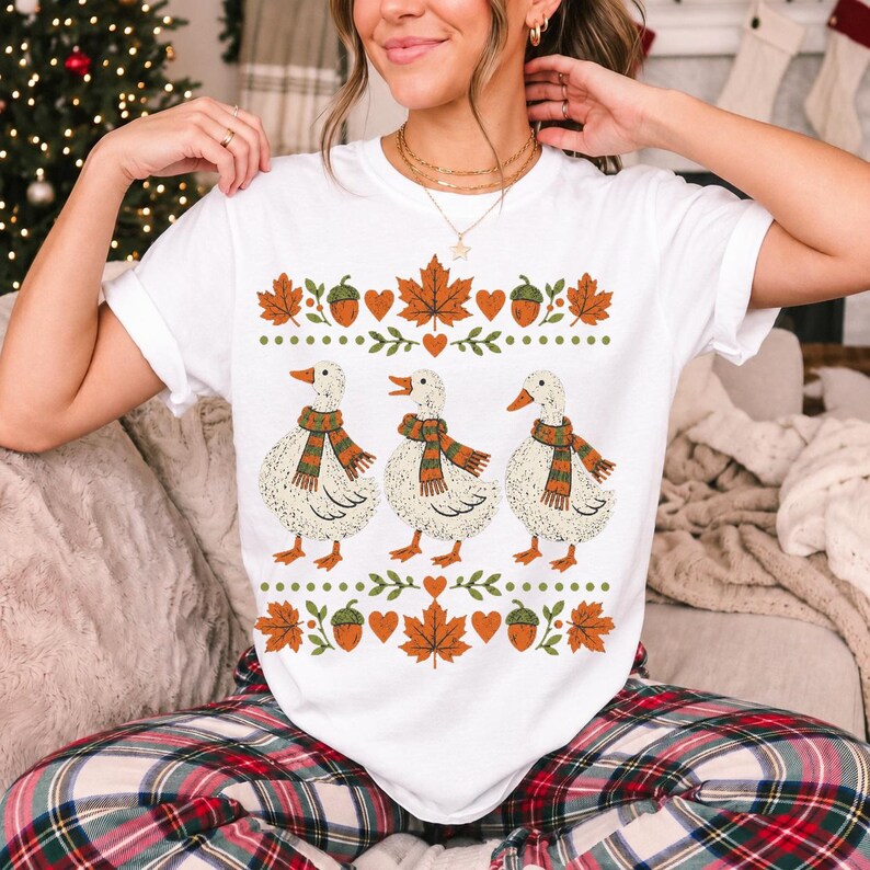 Three white ducks in striped scarves with acorn and maple leaf borders, retro screen print fall t-shirt art