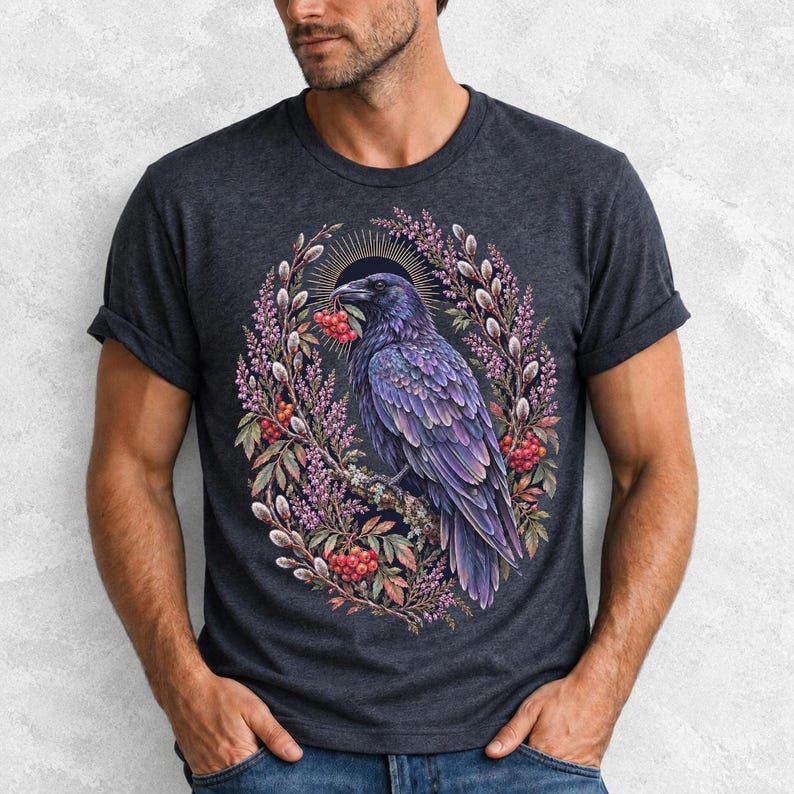 Raven holding a rowan berry inside an oval wreath of heather and catkins, painted cottagecore bird illustration