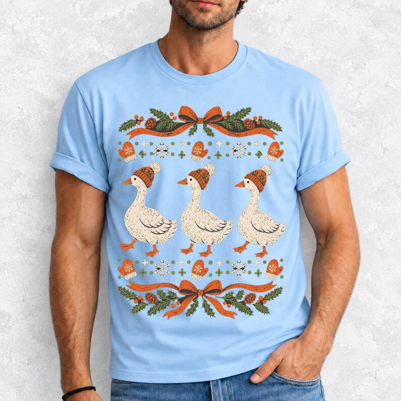 Three geese in pompom knit beanies with mittens, snowflakes and pine borders, retro winter t-shirt graphic