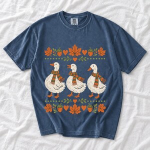 Three white ducks in striped scarves with acorn and maple leaf borders, retro screen print fall t-shirt art