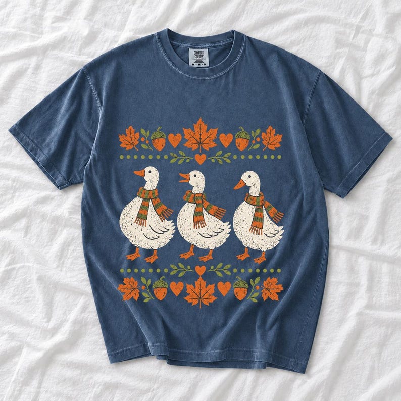 Three white ducks in striped scarves with acorn and maple leaf borders, retro screen print fall t-shirt art
