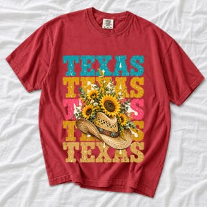 Straw cowboy hat full of sunflowers over a five-line stacked TEXAS word in retro western colors