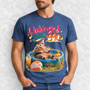 Opossum in party hat in a kiddie pool with cake, 90s film photo style, text "Unhinged Since 1990"
