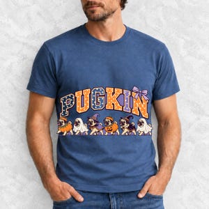 Six pugs in pumpkin, ghost and witch costumes under the arched word PUGKIN, lavender and orange polka-dot varsity style