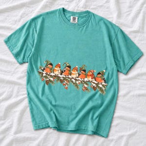 Watercolor bullfinches and robins in elf hats and scarves on a snowy pine branch