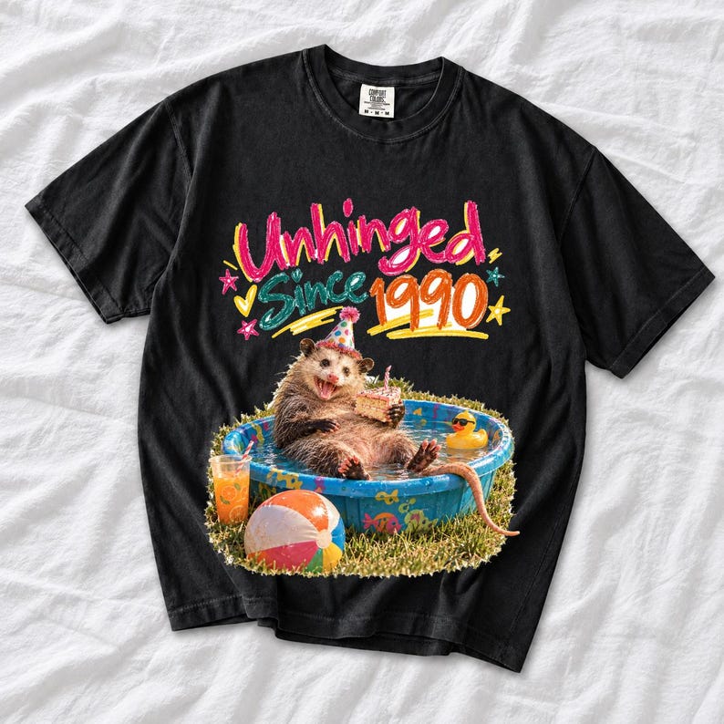 Opossum in party hat in a kiddie pool with cake, 90s film photo style, text "Unhinged Since 1990"