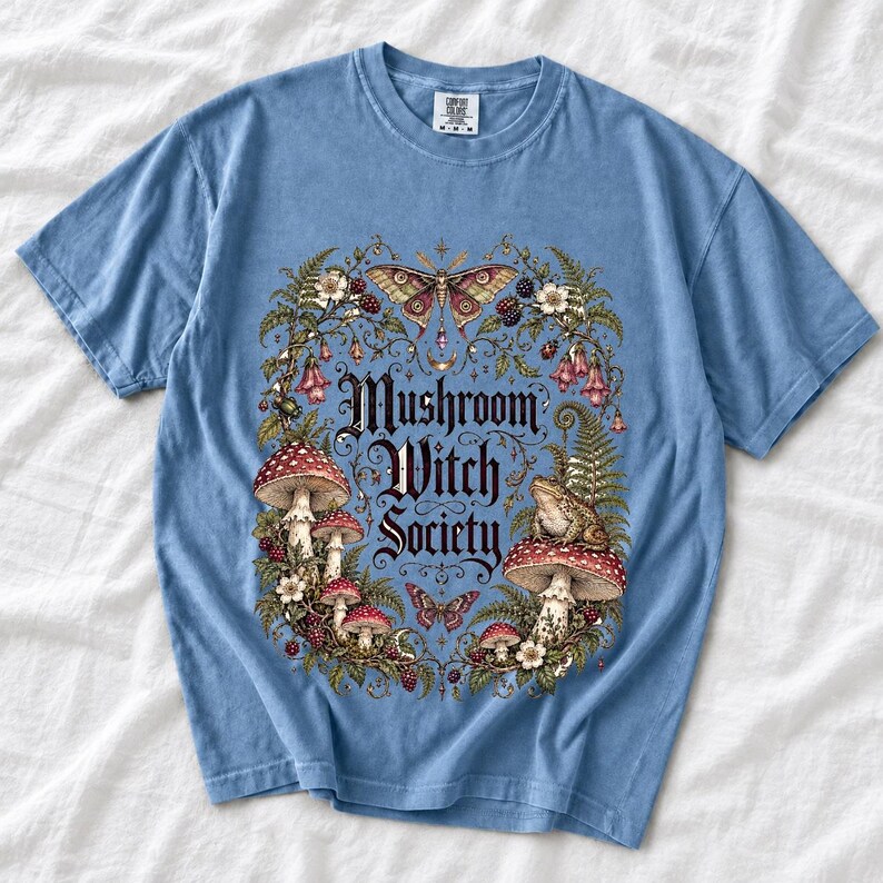 Blackletter text "Mushroom Witch Society" framed by fly agaric mushrooms, ferns and a toad on a mushroom cap