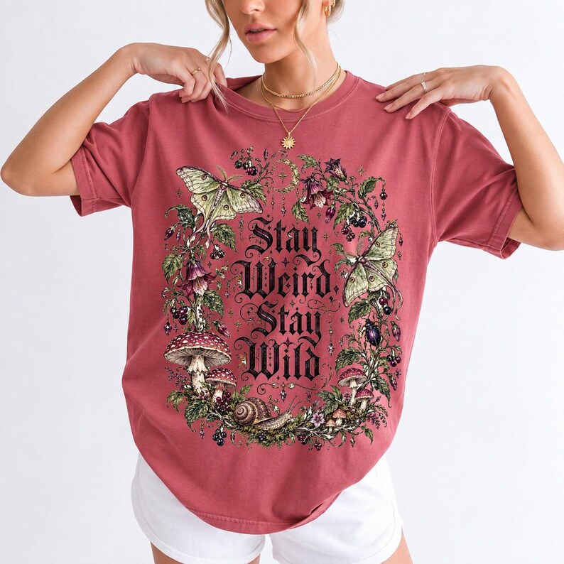 Victorian-style wreath of nightshade, luna moths and toadstools around the words "Stay Weird, Stay Wild"