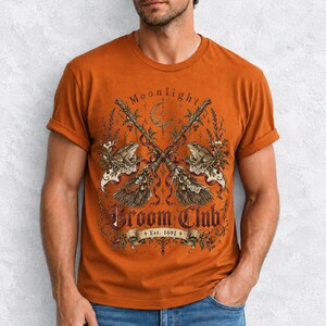 Vintage poster style crossed broomsticks with ribbons, lace and toads, text Moonlight Broom Club Est. 1692
