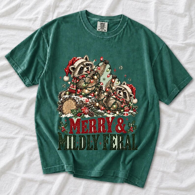 Two raccoons tangled in Christmas lights beside a log with the text Merry & Mildly Feral