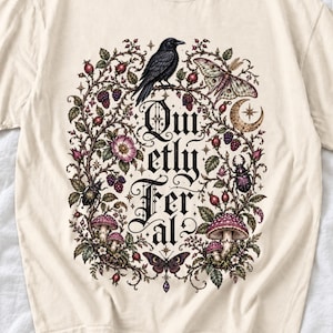 Raven on a wild rose branch with beetles and berries around blackletter text "Quietly Feral"