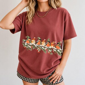 Watercolor bullfinches and robins in elf hats and scarves on a snowy pine branch