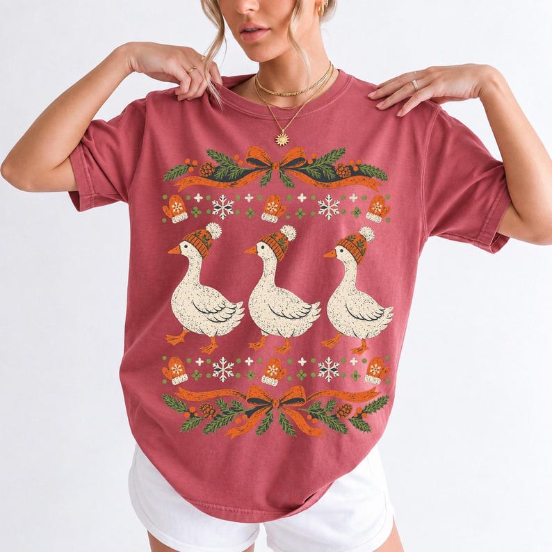 Three geese in pompom knit beanies with mittens, snowflakes and pine borders, retro winter t-shirt graphic