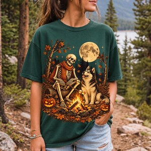 A skeleton in a scarf roasting marshmallows by a campfire beside a husky in an autumn forest under a full moon
