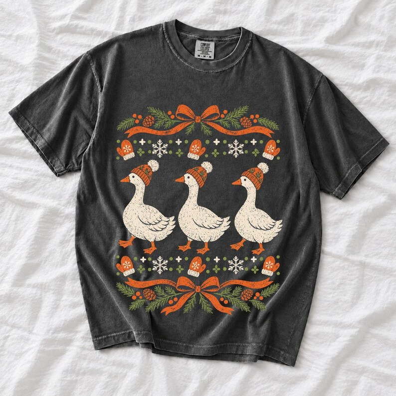 Three geese in pompom knit beanies with mittens, snowflakes and pine borders, retro winter t-shirt graphic