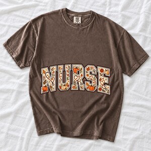 Arched varsity word NURSE filled with autumn leaves, stethoscopes and pumpkins in cream, rust and mustard