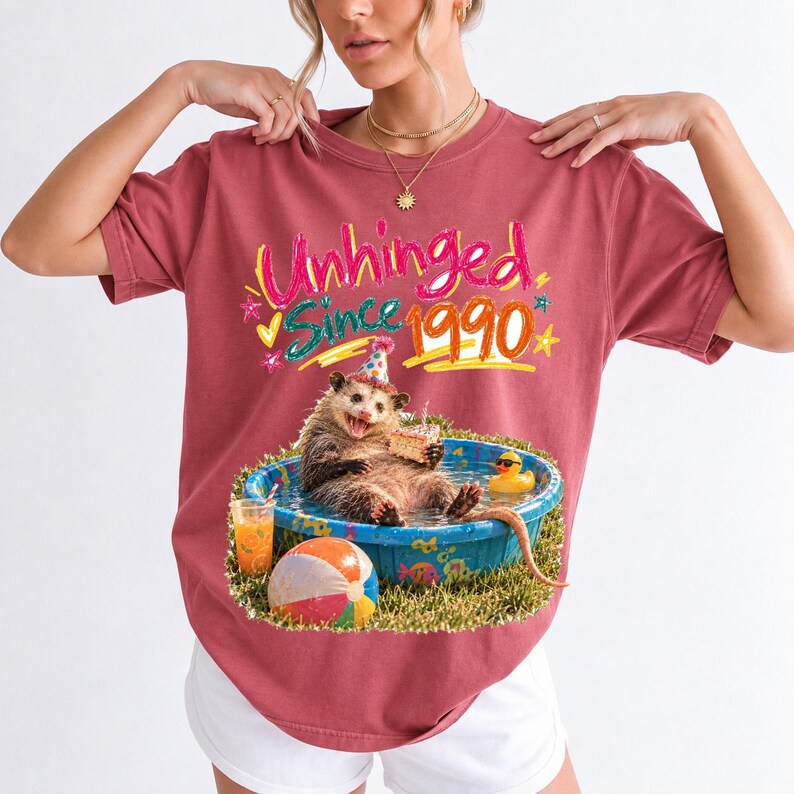 Opossum in party hat in a kiddie pool with cake, 90s film photo style, text "Unhinged Since 1990"