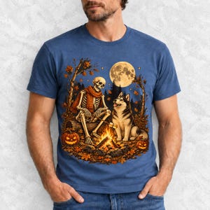 A skeleton in a scarf roasting marshmallows by a campfire beside a husky in an autumn forest under a full moon