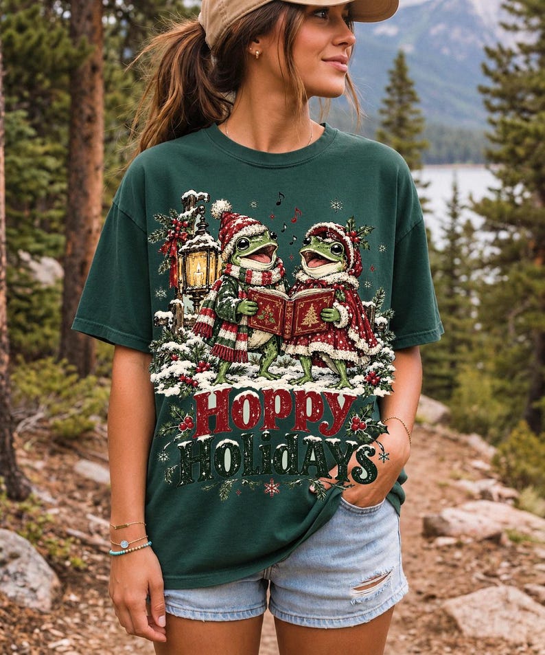 Two frogs singing carols in the snow with a lantern and songbook, text Hoppy Holidays