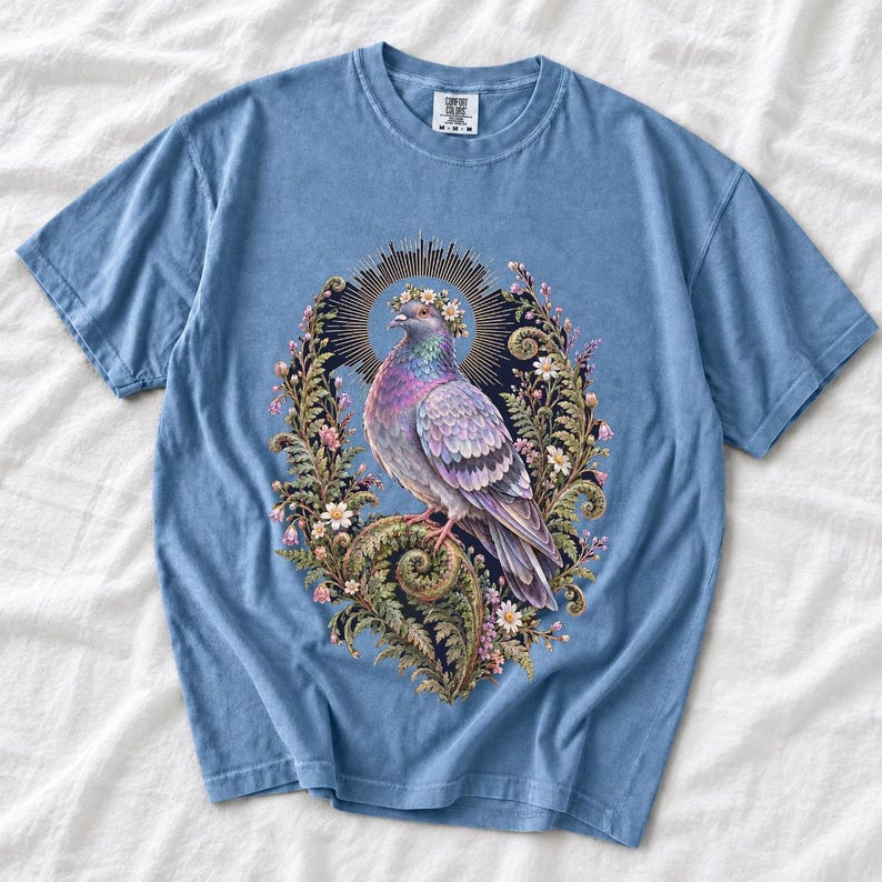 Painted pigeon wearing a daisy crown and glowing halo standing on a fern frond, whimsical cottagecore bird t-shirt art