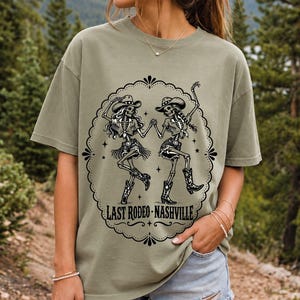 Two cowgirl skeletons in hats line dancing in a starry frame with the text Last Rodeo Nashville
