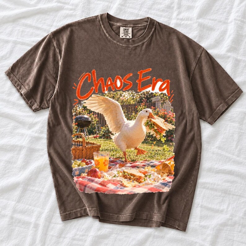 Goose stealing a sandwich from a picnic blanket, 90s film photo style, text "Chaos Era"
