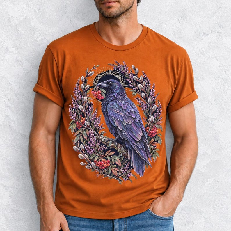Raven holding a rowan berry inside an oval wreath of heather and catkins, painted cottagecore bird illustration