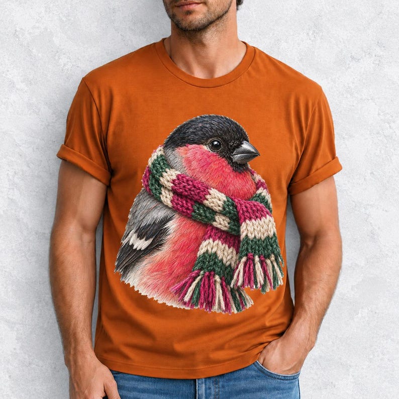 Colored-pencil bullfinch bird wrapped in a chunky striped knit scarf, cozy winter birdwatcher t-shirt art