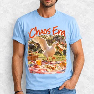 Goose stealing a sandwich from a picnic blanket, 90s film photo style, text "Chaos Era"