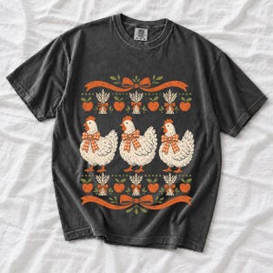 Three fluffy hens with gingham bows between apple and wheat borders, retro folk art fall t-shirt design