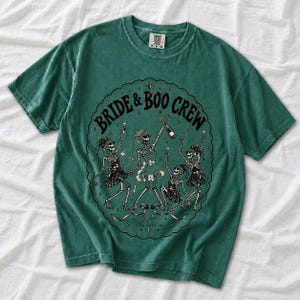 Skeleton bride popping champagne with cheering skeleton bridesmaids and the text Bride & Boo Crew
