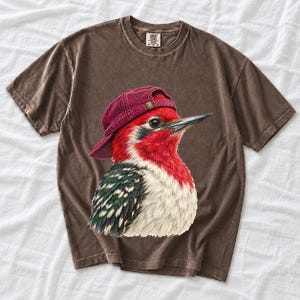 Colored-pencil red-headed woodpecker in side profile wearing a backwards corduroy cap, funny birder t-shirt graphic