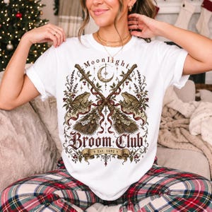 Vintage poster style crossed broomsticks with ribbons, lace and toads, text Moonlight Broom Club Est. 1692