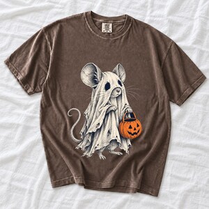 Etched pen illustration of a small mouse in a sheet ghost costume holding a candy bucket, bone white with orange accent