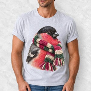 Colored-pencil bullfinch bird wrapped in a chunky striped knit scarf, cozy winter birdwatcher t-shirt art