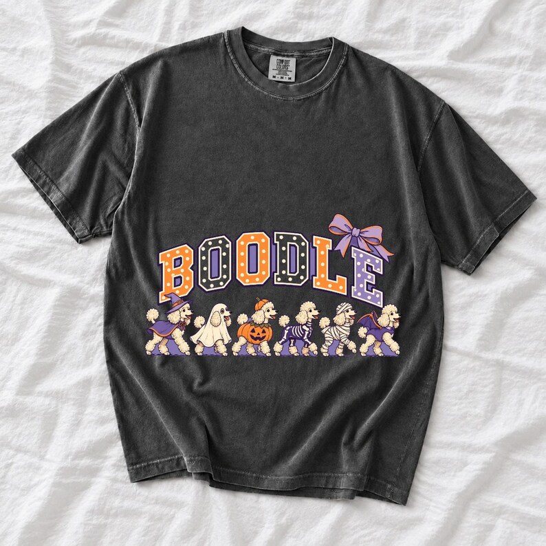 Six poodles in Halloween costumes walking under the arched word BOODLE, lavender and orange polka-dot varsity style
