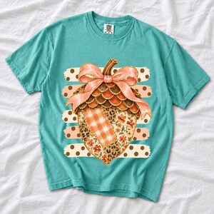 Giant patchwork acorn with a pink satin bow made of plaid, leopard and floral fabric on polka-dot stripes