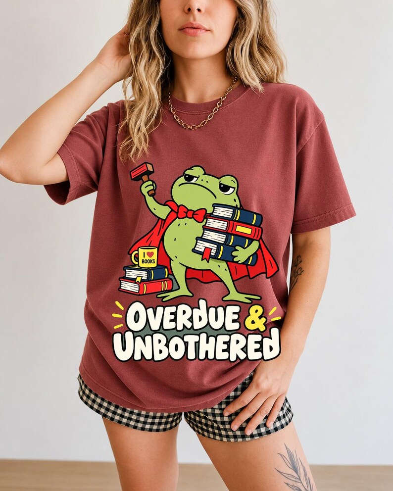 Grumpy cartoon frog librarian holding a stamp and a stack of books with the text Overdue & Unbothered